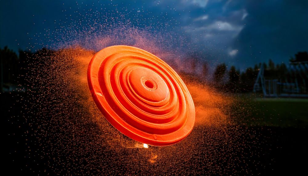 Orange clay pigeon breaking in mid-air