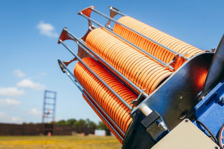 Automatic clay trap loaded with orange targets against a blue sky